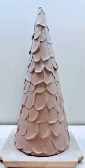 A tall cone-shaped clay tree covered in overlapping hand-cut scales